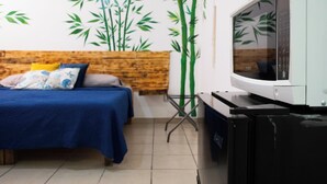 A room with a bed, a wooden headboard, a television, and a wall with bamboo decals. - Isla Venados Renta Vacacional (Mazatlán)