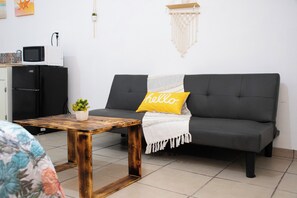 A modern living room with a grey sofa, a wooden coffee table, a small potted plant, and a 'hello' pillow. - Isla Venados Renta Vacacional (Mazatlán)