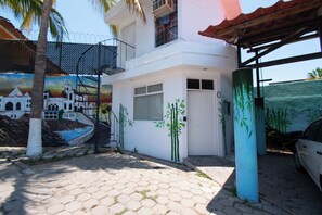 A white building with a mural, a covered area, and a parked car. - Isla Venados Renta Vacacional (Mazatlán)