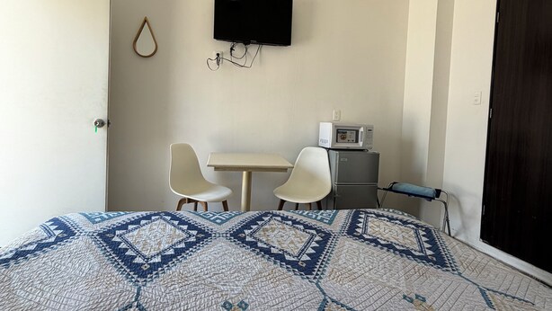 A hotel room with a bed, a television, a microwave, and two chairs. - Isla Venados Renta Vacacional (Mazatlán)