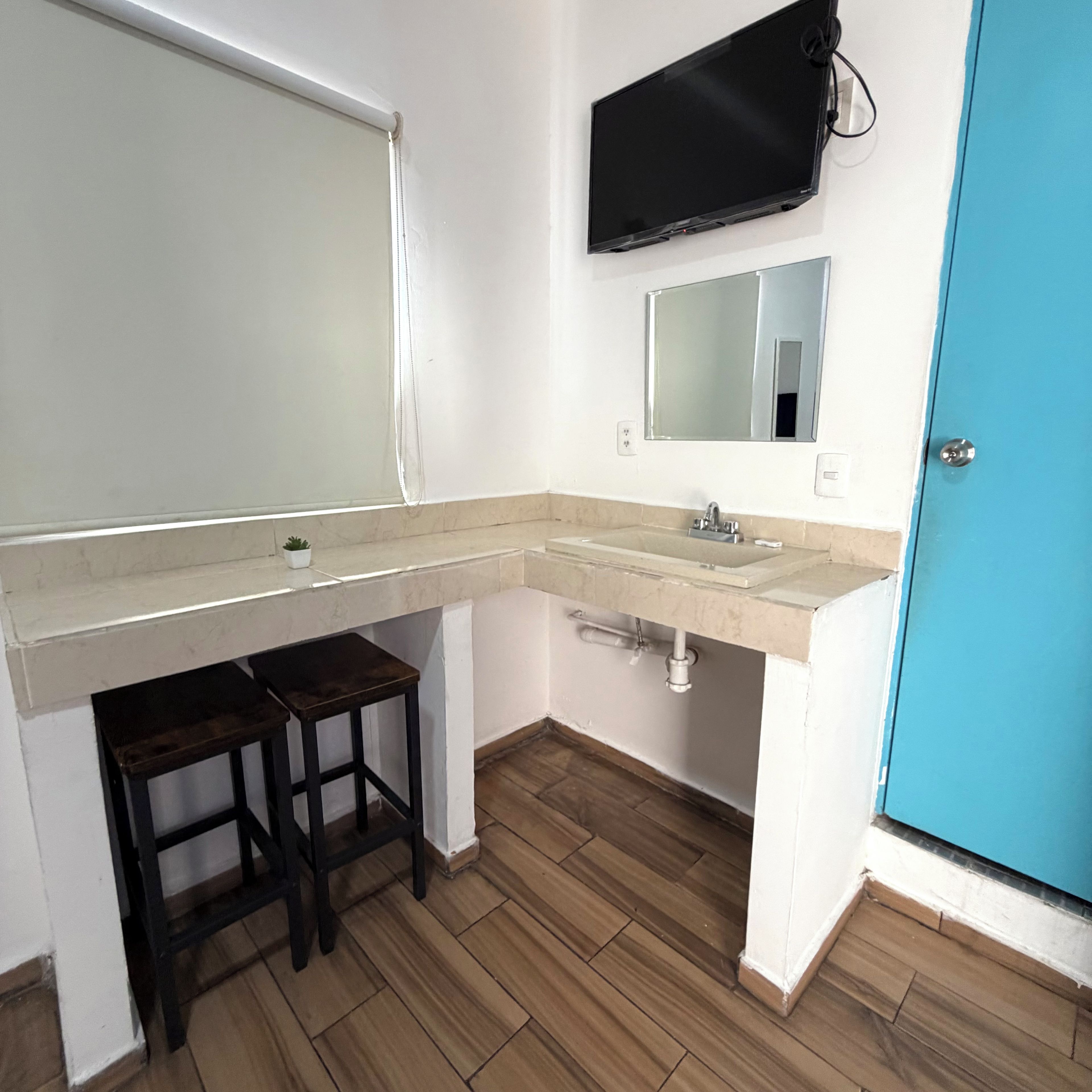 Une salle de bain avec un lavabo, un miroir et une porte bleue.
