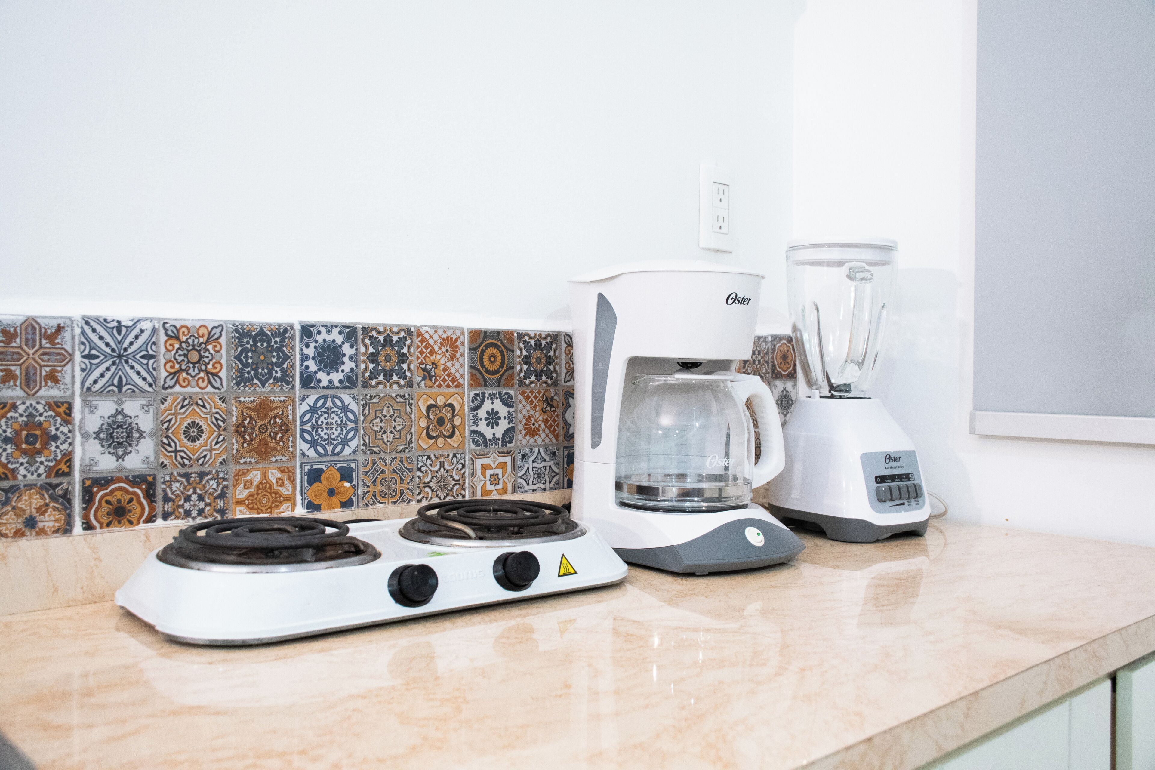 Una cocina con estufa a gas, cafetera y licuadora en la encimera.
