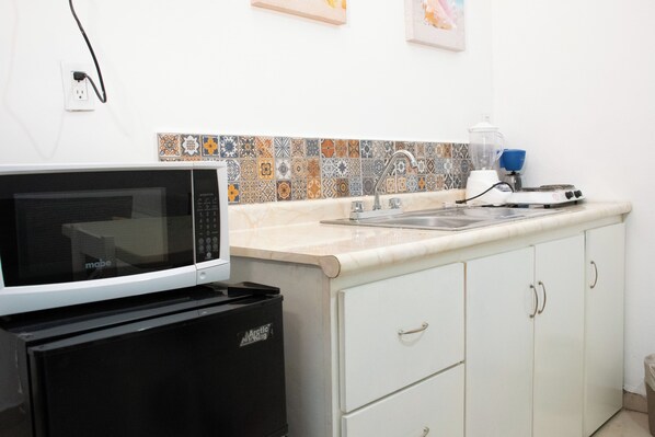 A kitchen with a microwave, a blender, and a sink.