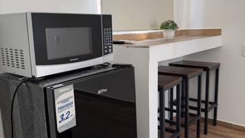 Une petite cuisine équipée avec un four à micro-ondes, un petit évier et des tabourets de bar.