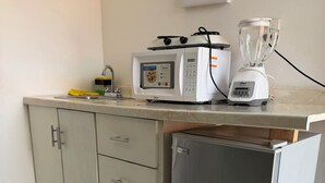 A kitchenette with a microwave, toaster, and blender on the countertop, a refrigerator below, and a cabinet with drawers. - Isla Venados Renta Vacacional (Mazatlán)