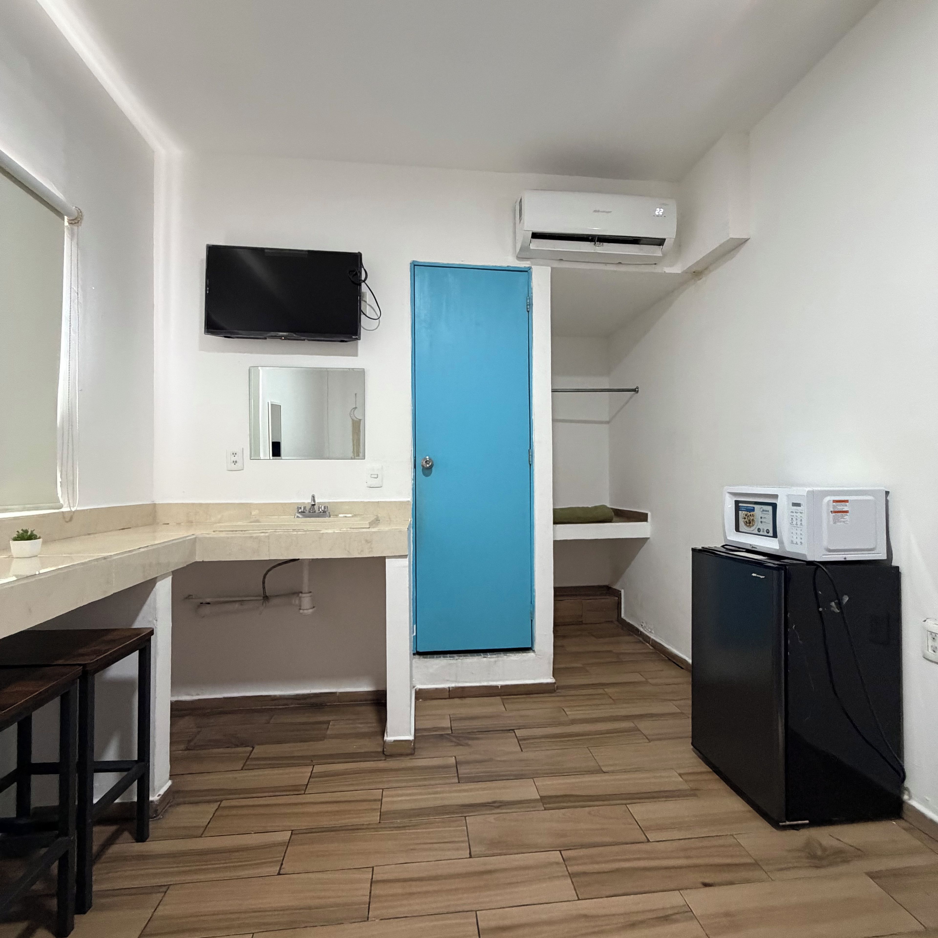 Una cocina compacta con un lavamanos, un microondas y un refrigerador.