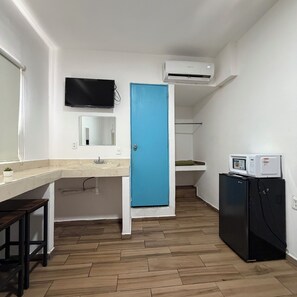 Cozinha compacta com pia, micro-ondas e geladeira.