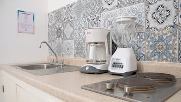 Una cocina con un lavamanos, una cafetera y una licuadora en la encimera.