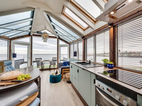 A modern kitchen with a large island, a dining area with a view, and a built-in oven.