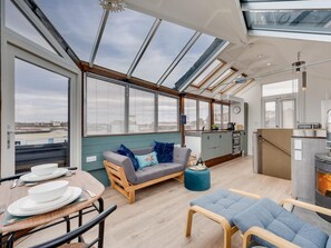A modern interior with a skylight, a sofa, a dining table, and a fireplace.