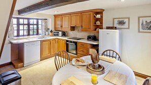 Una cocina con armarios de madera, una mesa de comedor con sillas y un refrigerador.