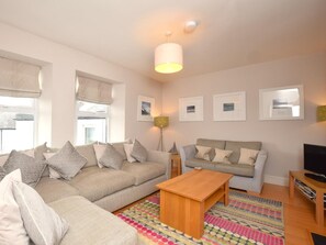 A living room with a sofa, a coffee table, a TV stand, and framed pictures on the wall. - 3 Bed in Alnwick (oc-94013) (Alnmouth)
