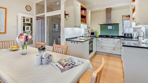 A modern kitchen with white cabinets, a dining table with chairs, and a kitchen island. - 3 Bed in Alnwick (oc-94013) (Alnmouth)