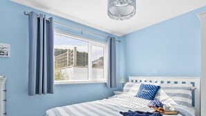 Ein Schlafzimmer mit Bett, Vorhängen, einem Fenster und einer Kristallleuchter.