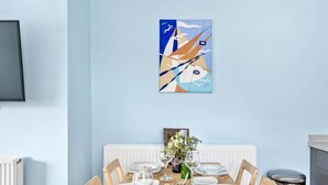 Ein Esszimmer mit gedecktem Tisch für sechs Personen, einem Gemälde an der Wand und einem Heizkörper darunter.