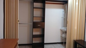 Ein Zimmer mit Schiebetürenschrank, einem kleinen Tisch und einem Regal.