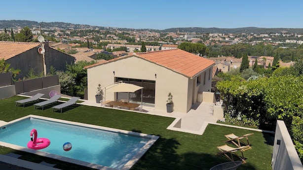 Una casa moderna con piscina, mobiliario de exterior y vista a un pueblo.