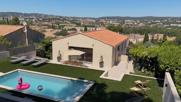 Une maison moderne dotée d’une piscine, d’un espace salon extérieur et offrant une vue sur la ville.