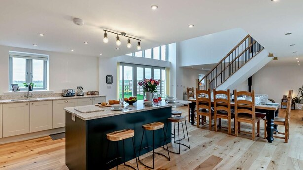 A spacious kitchen with a large island, wooden dining area, and a staircase leading to an upper level. - 4 Bed in Brough (oc-93496) (Brough)