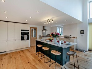 A modern kitchen with a central island, wooden flooring, and recessed lighting.