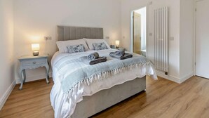 A bedroom with a bed, bedside tables, a nightstand, a lamp, a radiator, and a door. - 4 Bed in Brough (oc-93496) (Brough)