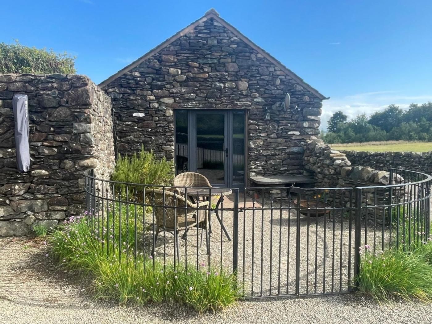 A stone cottage with a fenced patio, a door, and a window.
