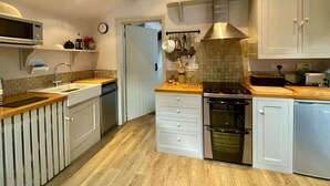 Une cuisine moderne avec des meubles blancs, un four encastré, un four à micro-ondes et un plan de travail en bois.