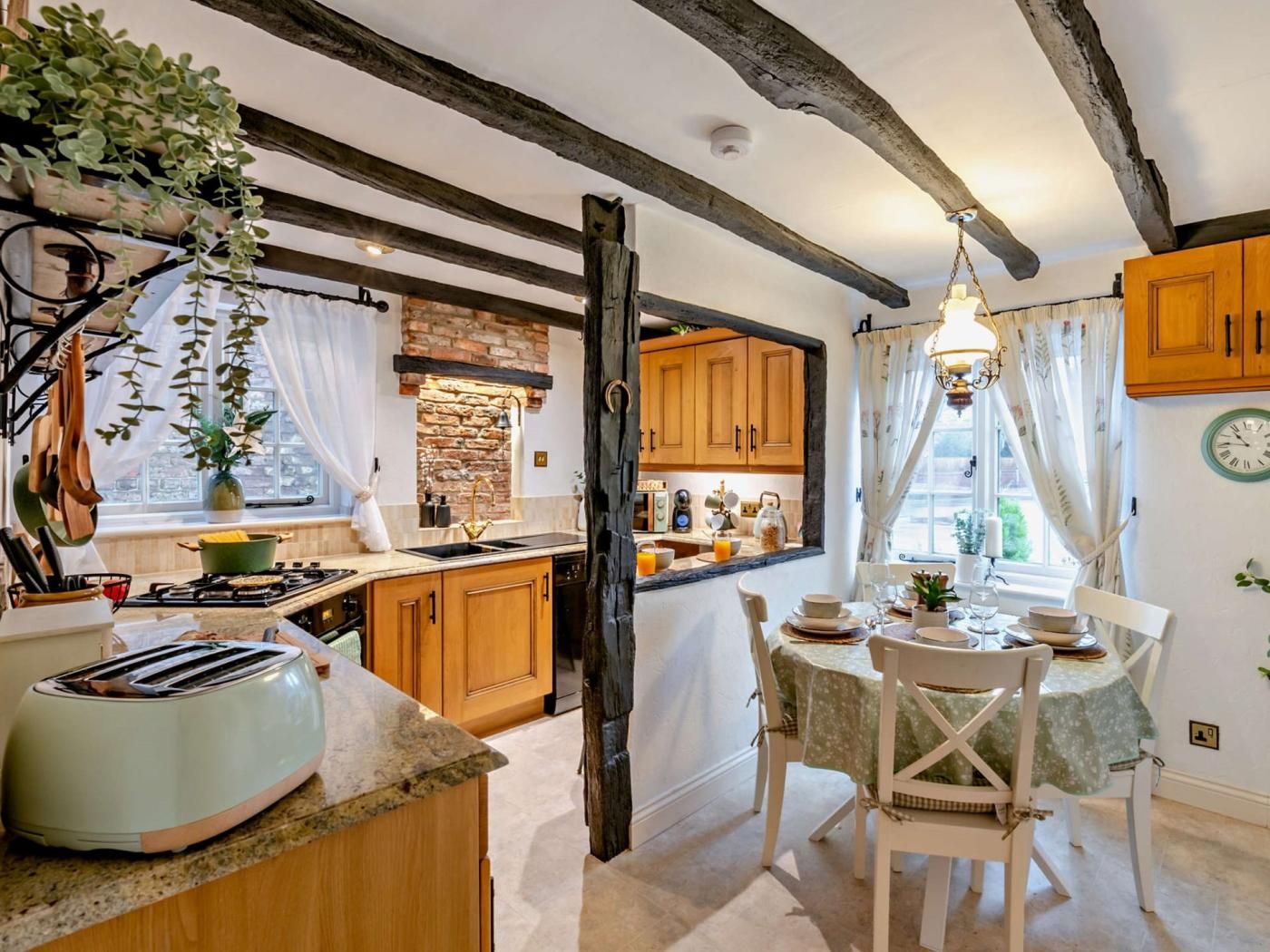 A kitchen with wooden cabinets, a stone backsplash, and a dining area with a table set for two.