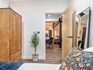A bedroom with a bed, a wooden wardrobe, a potted plant, and a door leading to a dining area. - 2 Bed in High Peak (oc-94059) (New Mills)