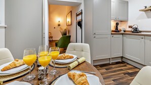Una cocina moderna con armarios blancos, una mesa de comedor lista para el desayuno y una zona de estar acogedora.