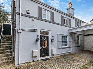 A two-story building with a black front door, white shutters, and a stone staircase leading to the entrance. - 4 Bed in Torquay (oc-94002) (Torquay)