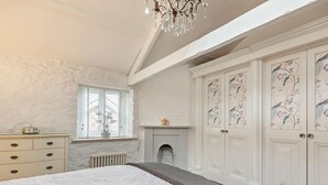 Un dormitorio con una cama grande, un aparador, una chimenea y un conjunto de puertas con diseños florales.