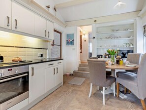 Una cuina moderna amb armaris blancs, un forn Bosch i una zona menjador amb taula i cadires.