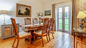 Un comedor con una mesa y sillas de madera, un jarrón con flores y un cuadro en la pared.