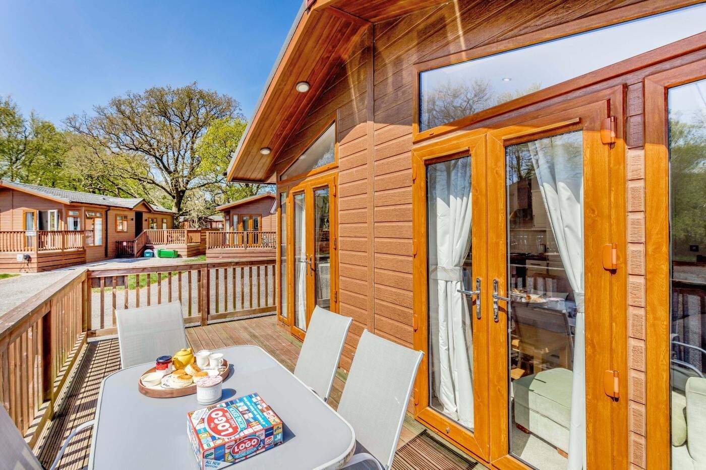 A wooden deck with a table and chairs, a dining set, and a board game.