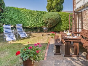 A patio with a wooden table and benches, a barbecue grill, and two striped lounge chairs. - 2 Bed in Hereford (oc-94018) (Dorstone)