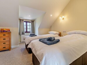 A bedroom with two beds, a wooden dresser, a window with curtains, and a wall-mounted light fixture. - 3 Bed in Great Yarmouth (oc-94054) (Repps with Bastwick)
