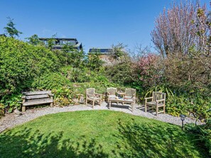 A garden with a seating area, a lawn, and a building in the background. - 2 Bed in St. Ives (oc-rgton) (Carbis Bay)