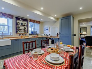 A well-lit kitchen with a dining table set for breakfast, featuring plates, cups, and a fruit bowl. - 2 Bed in Huntly (oc-93789) (Huntly)