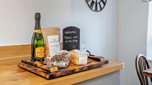 A wooden counter with a bottle of Proccini wine, a Beadlam Grange coffee bag, a chocolate bar, and a welcome sign. - 2 Bed in York (oc-93614) (Beadlam)