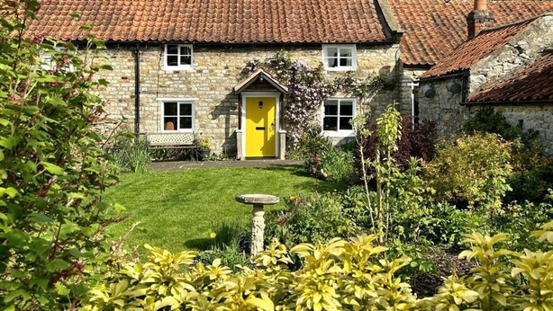 A stone house with a yellow door, a tiled roof, and a well-maintained garden. - 2 Bed in York (oc-93614) (Beadlam)