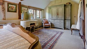 Une chambre à coucher comprenant un lit, une commode, une chaise, un grand miroir et une armoire.