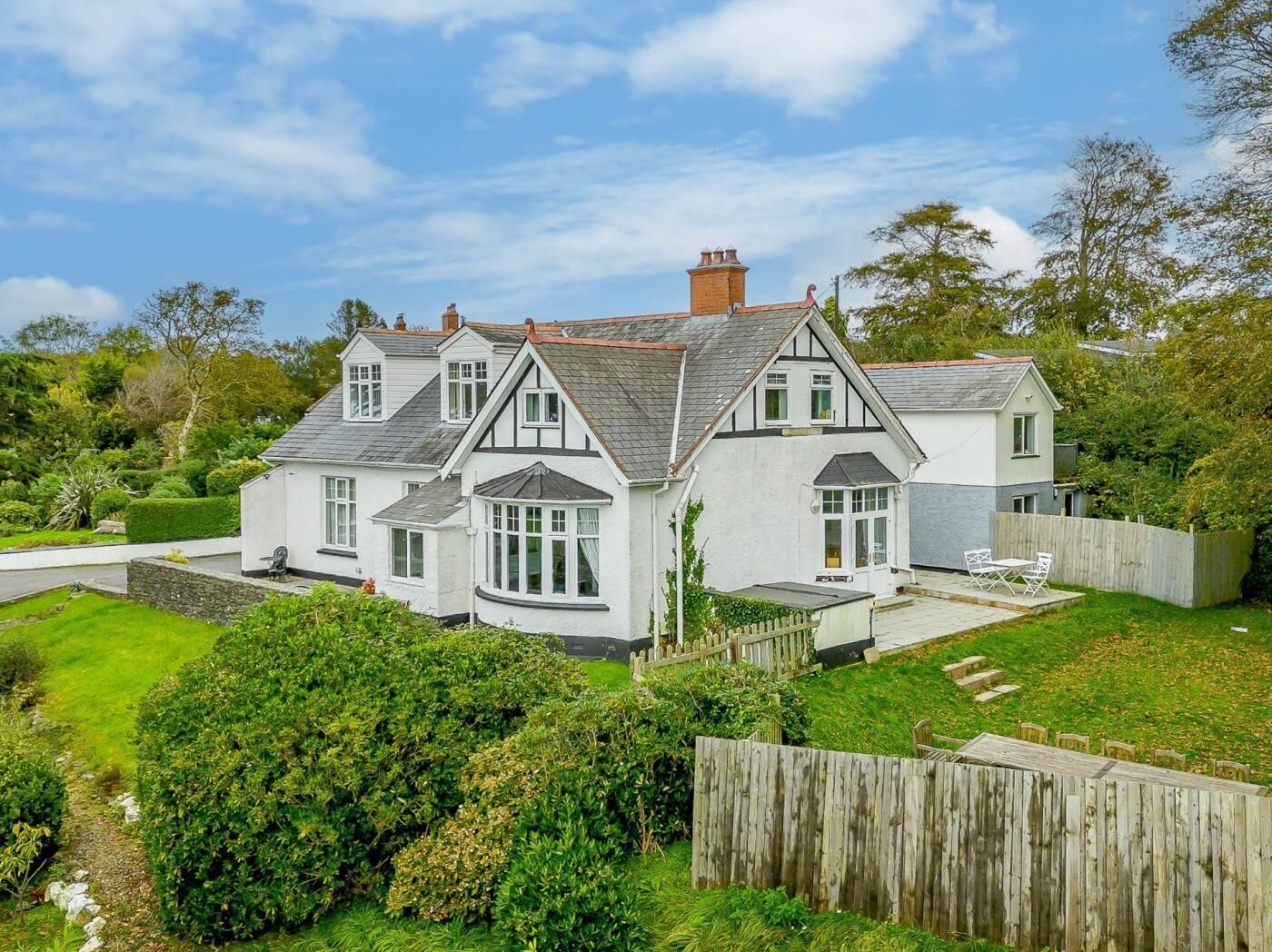 A two-story house with a white exterior, multiple windows, and a fenced backyard.