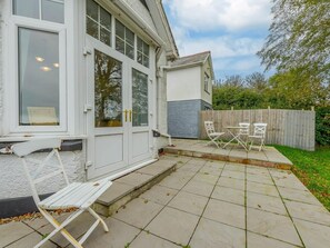 Ein Wohnhaus mit Terrasse, Fenstern mit weißen Rahmen und einem Holzzaun.