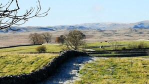 A stone wall leading through a grassy field with distant hills. - 3 Bed in Penrith (oc-74159) (Shap)