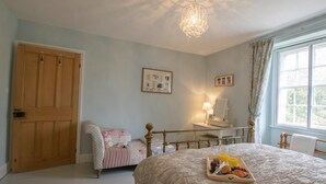 A bedroom with a bed, a bedside table, a chair, a wooden wardrobe, and a window. - 3 Bed in Penrith (oc-74159) (Shap)
