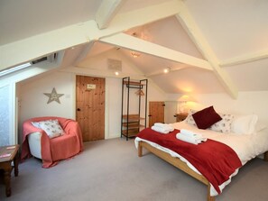 A bedroom with a sloped ceiling, a bed with a red and white bedspread, a wooden chair, and a star-shaped wall decoration. - 3 Bed in Penrith (oc-74159) (Shap)