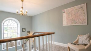 A room with a staircase, a map on the wall, a window, and a chair. - 3 Bed in Penrith (oc-74159) (Shap)