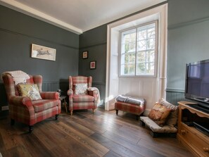 A room with two armchairs, a small table, a bench, a television, and a large window. - 3 Bed in Penrith (oc-74159) (Shap)