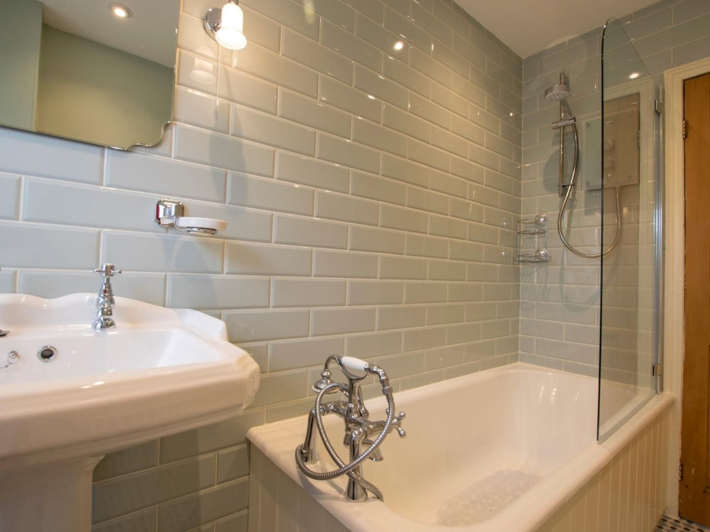 A bathroom with a white sink, a bathtub, and a glass-enclosed shower area.